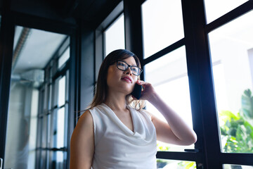 Fototapeta premium Asian woman having a phone call and looking outside