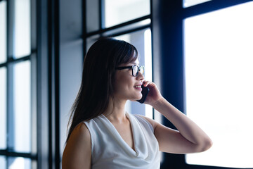 Obraz premium Asian woman having a phone call and looking outside