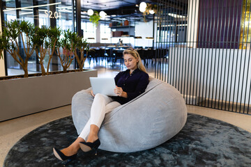 Caucasian woman using a laptop in a bean bag