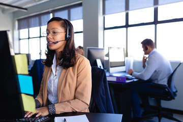 African American woman working with headset phone in office