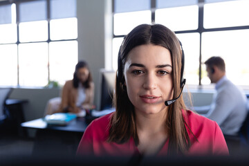 Caucasian woman working with headset phone in office