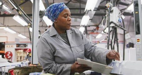 African American female car mechanic painting a body of a car - Powered by Adobe