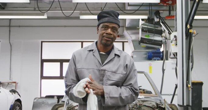 African American male car mechanic cleaning his hands with a rag 