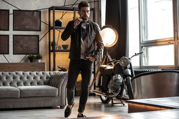 Perfect man. Young hipster in leather jacket standing in room.