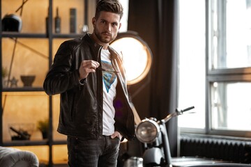 Fototapeta na wymiar Perfect man. Young hipster in leather jacket standing in room.