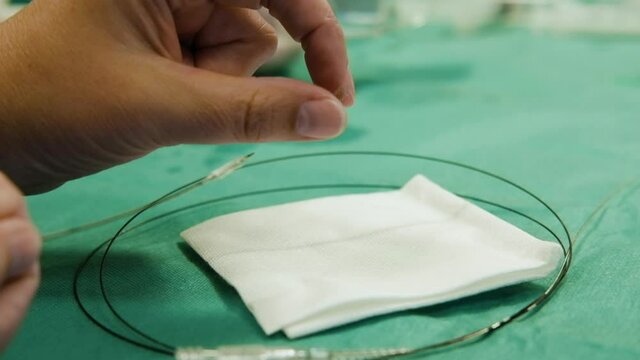 Doctor pulls off stent from small balloon, inspecting the tiny metal equipment, treatment for coronary heart disease