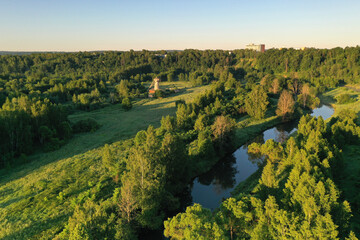 panoramic view of green meadows a large wooden mill in the morning haze at sunrise shot from a drone at dawn