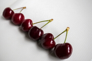 Obraz na płótnie Canvas Three pairs of sweet red cherries arranged in a row on a white background. Food and drink concept