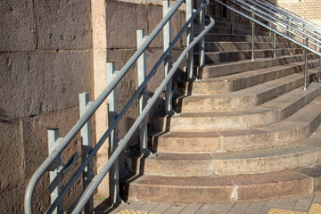 A staircase with concrete steps and a steel railing descends to the sidewalk