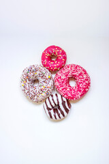 Top view of four donuts on white background. Glazed donuts or doughnuts set - various colors and tastes 3d rendering. Cute, colorful and glossy donuts with glaze and powder.