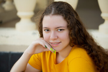 Portrait of a curly brunette in a yellow t-shirt