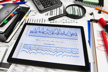 Top view of office employee's desk - work with tablet pc computer and financial reports, analysis and accounting, tables and graphs, various office items for bookkeeping