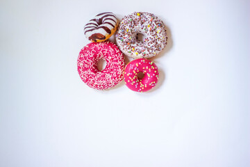 Obraz na płótnie Canvas Sweets donuts sugar glazed. Delicious colorful donuts isolated on white background. Assorted donuts with chocolate frosted, pink glazed and sprinkles donuts. Top view. Space for text.