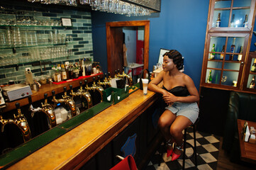 Portrait of african american woman, retro hairstyle posing at restaurant on bar counter with cup of latte.