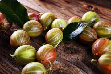 Gooseberries fruits on wooden background. Red and green ripe gooseberries on background
