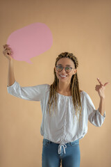 Happy young African American female in eyeglasses holding pink dialogue cloud, pointing her index...