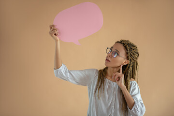 Young African American female in eyeglasses holding pink dialogue cloud, touching her chin with...