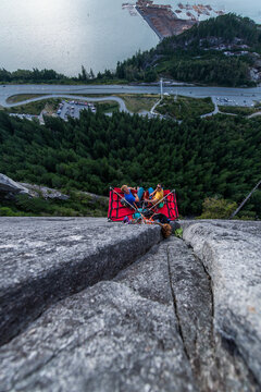Top view of two men looking up and sitting on portaledge at sunset