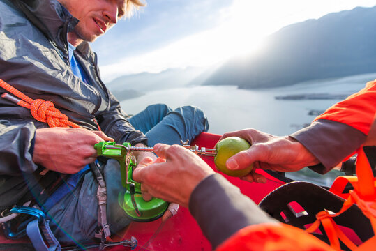 two men using an apple peeler sitting on portaledge at sunset