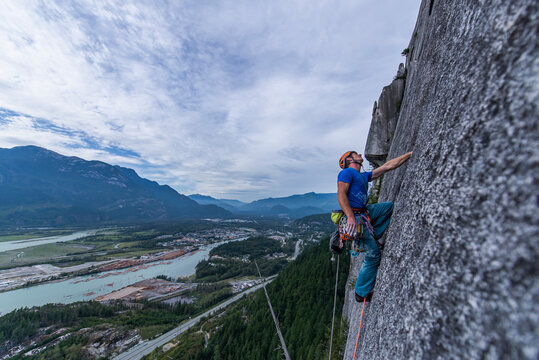 Man looking up while rock climbing Squamish Chief on granite with view
