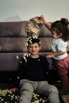 some kids watch a movie at home while eating popcorn, little sister th