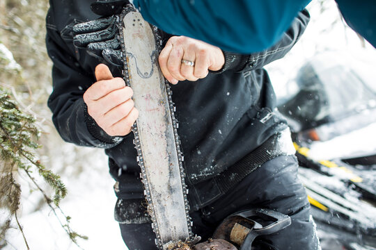 Arborist fixing chain on chainsaw outdoors.