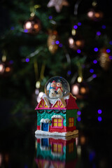 Christmas scene with tree, lights and snow globe. Selective focus on black background.