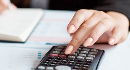 Businesswoman using a calculator to calculate the numbers