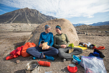 Climbing partners share a laugh during mealtime at campsite.