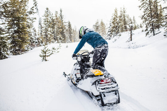 Rear view of man snowmobiling in winter weather.