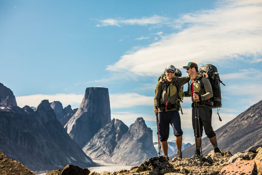 Two happy backpackers laugh while on high mountain ridge with view.
