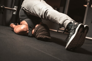 Fototapeta premium A sporty man in the gym is doing relaxation of yoga and martial arts exercises. Yoga mental benefits. Halasana Position.(Plough Pose)