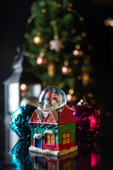 Christmas scene with tree, lights and snow globe. Selective focus on black background.