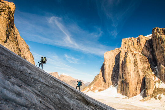 Backpackers hiking up glacier, ascending Mount Asgard, Baffin Island.