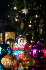 Christmas scene with tree, lights and snow globe. Selective focus on black background.