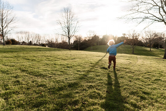 Young child frolicking in field of green grass