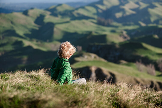 Blond curly haired child looking at view of green hills