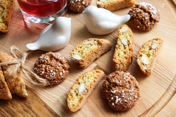 Traditional italian cantuccini cookies with almonds and dried cranberries with a glass of red sweet wine on a wooden background. Home baking concept.
