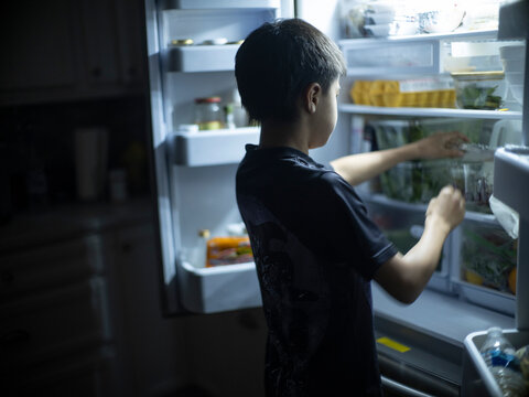 A 12 Year-old Boy Searches In Fridge For Late Night Snack