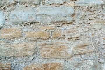 An old wall made of boulders or stones with cement or mortar is ideal for background and texture.