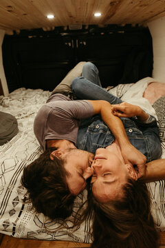 intimate moment as newly engaged couple lay on bed together for kiss