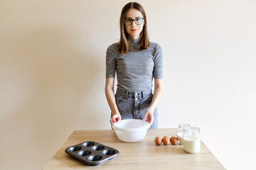 woman in t-shirt and jeans preparing homemade cupcakes in her kitchen