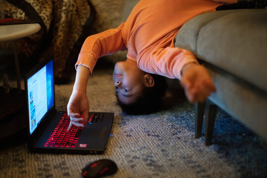A 12-year old boy in an unusual body position uses a laptop computer