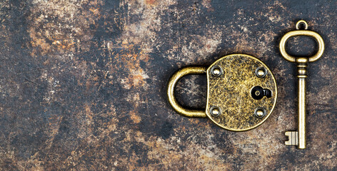 Escape room game concept. Web banner of a vintage gold key and locked padlock on a rusty metal background.