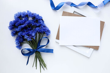 postcard mockup. bouquet of blue cornflowers and an envelope isolated on white background. place for text