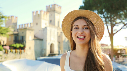 Portrait of smiling tourist woman with Sirmione Castle on the background, Lake Garda, Italy