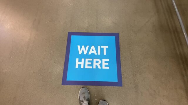 A view of a social distance reminder sticker on the floor at a checkout line in a big box warehouse store. Social distancing was a common practice to reduce the spread of COVID-19 during the pandemic 
