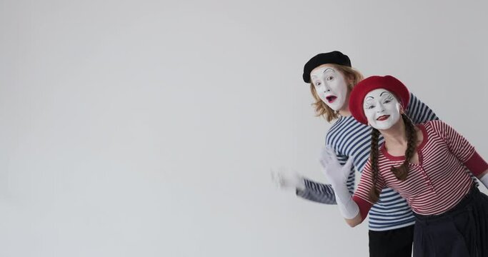 Excited mime artist couple greeting by waving hands and inviting to come 