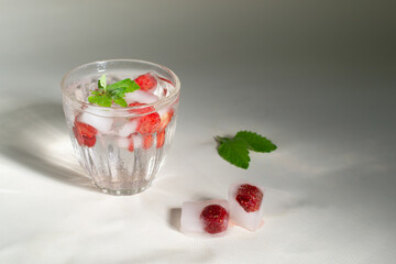 A glass of homemade frozen strawberry lemonade with ice cubes and mint leaves on a white background. Cold flight drink. Copy space. Horizontal orientation.