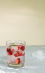 Homemade frozen strawberry lemonade with ice cubes and a sprig of mint on a gray background. A refreshing summer drink. Copy space. Vertical orientation.